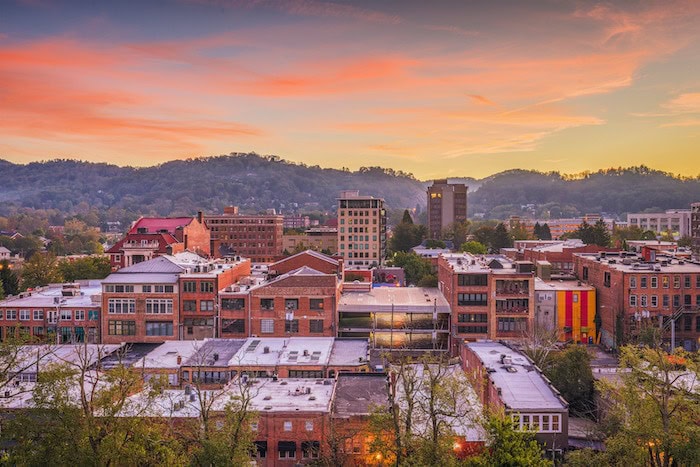 Aerial view of Asheville, North Carolina at sunset with brick homes in the foreground and the Blue Ridge beyond