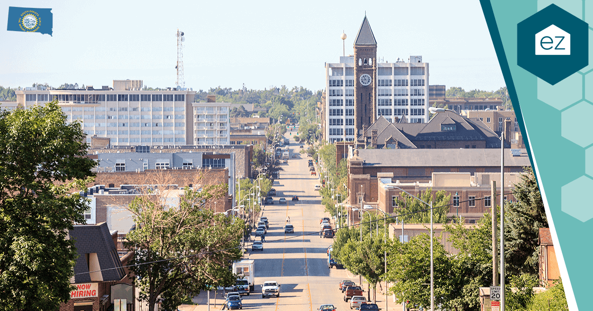 Tree-lined downtown street in South Dakota with a clock tower and parked cars, in the state's largest metro
