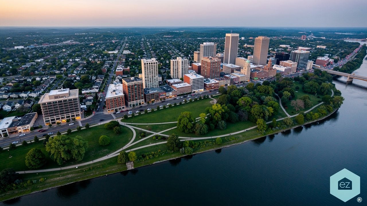 Aerial view of an Oklahoma downtown skyline with a riverfront park and walking paths at dusk