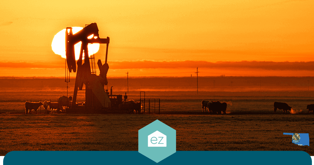 An oil pumpjack operating in an Oklahoma field at sunset with cattle grazing nearby