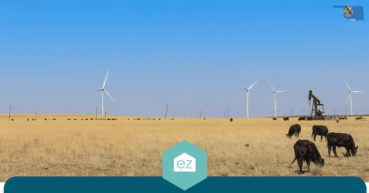 Cattle grazing in an Oklahoma field with wind turbines and an oil pumpjack in the background