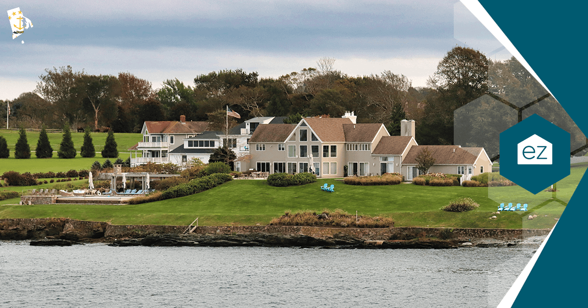 Large waterfront home with manicured lawn and chairs facing the water in coastal Rhode Island