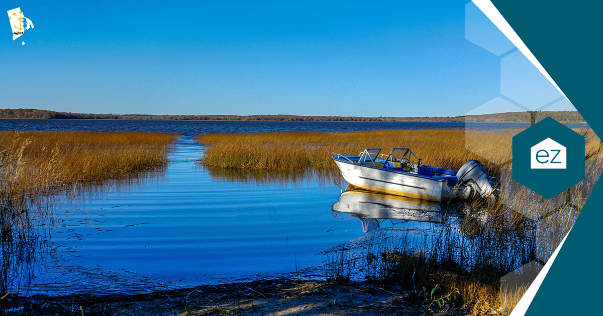 Small motorboat docked among tall reeds on a calm Rhode Island lake under a clear sky