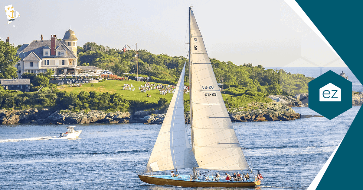 A sailboat passing a large waterfront home with lawn and trees on the Newport, Rhode Island shoreline