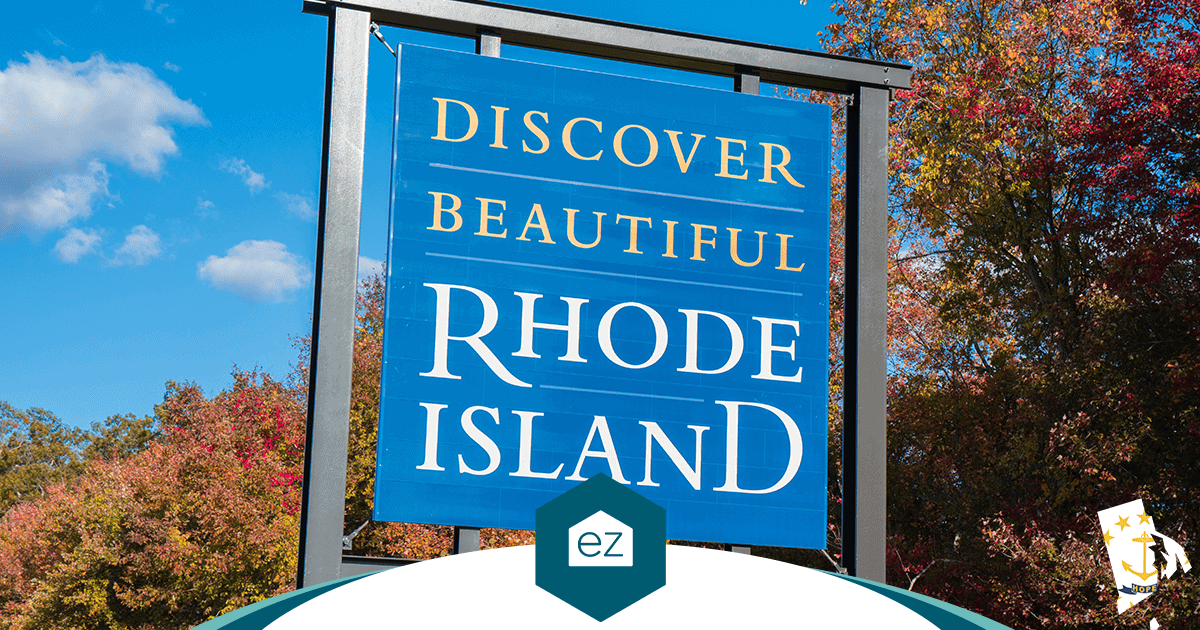 Blue Rhode Island welcome sign set against trees showing autumn color