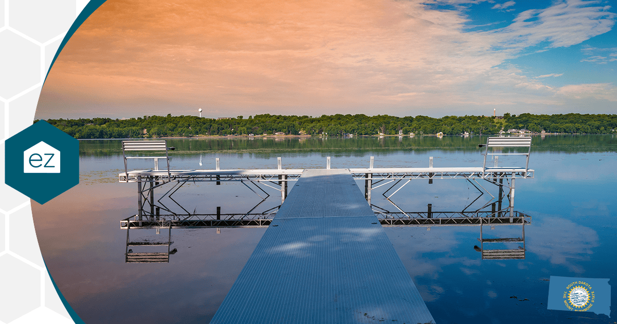 Dock extending over calm South Dakota water with green trees along the far shore