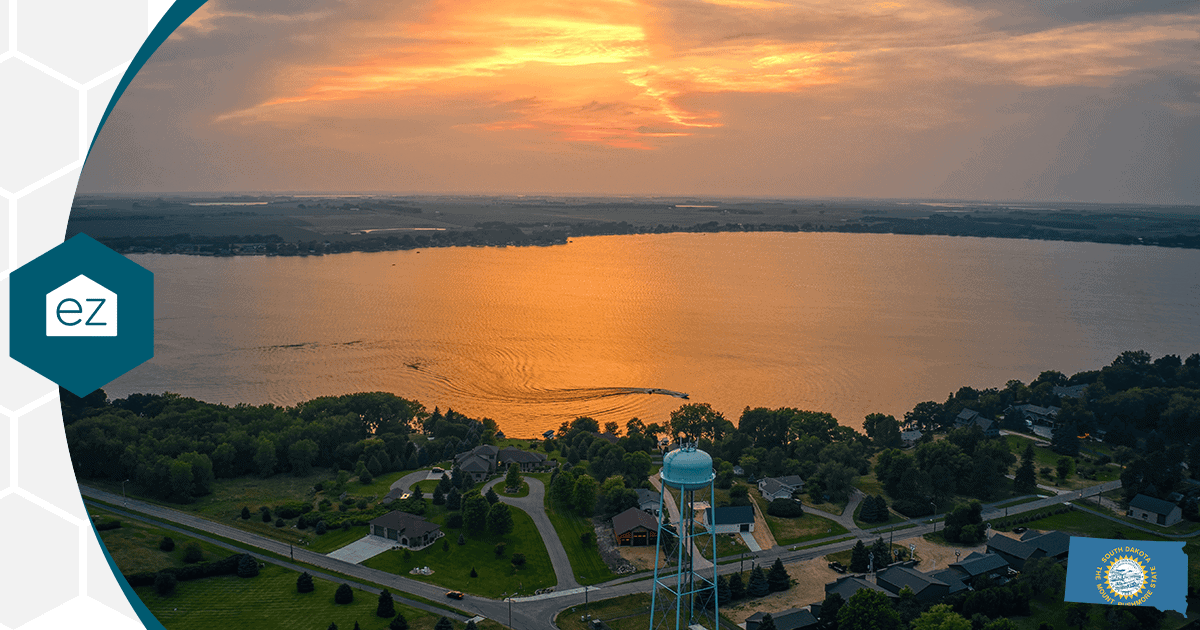 Aerial view of a South Dakota lakeside town at sunset with homes, trees and a water tower