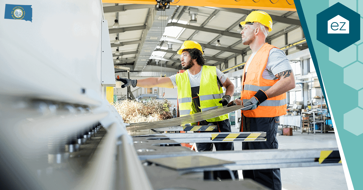 Two workers in safety vests operate machinery in a South Dakota manufacturing plant, one of several sectors supporting the state's housing demand