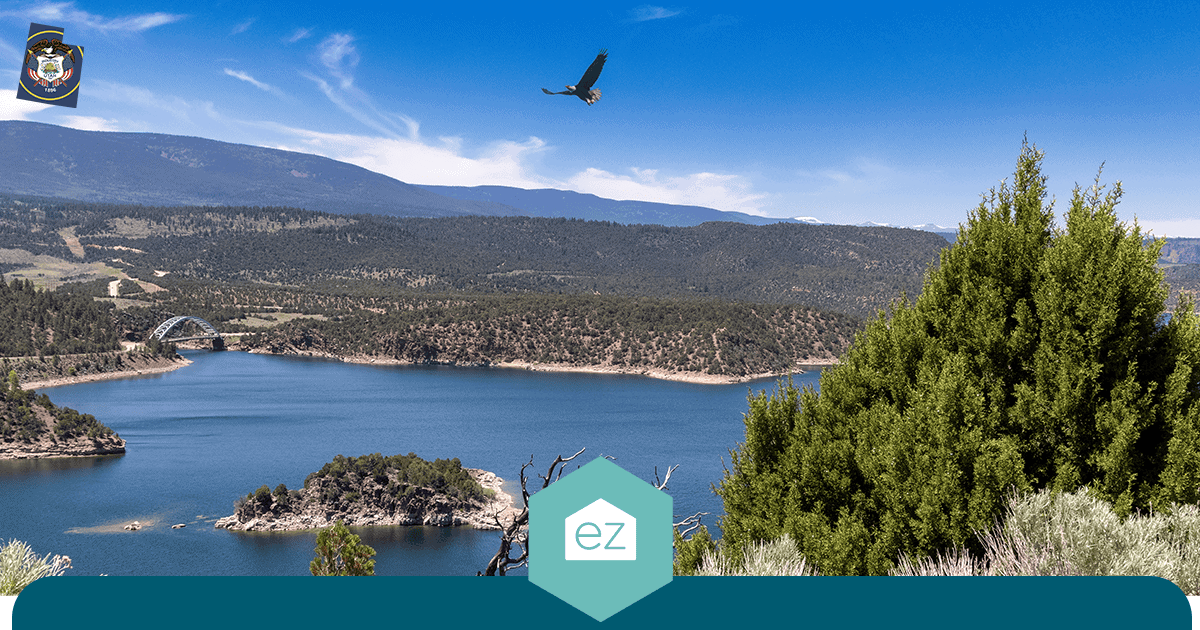 A Utah mountain lake ringed by trees and hills with a bridge crossing one end