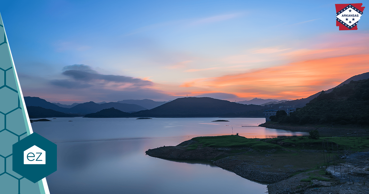 A calm Arkansas lake at sunset surrounded by hills, evoking the state's waterfront communities.