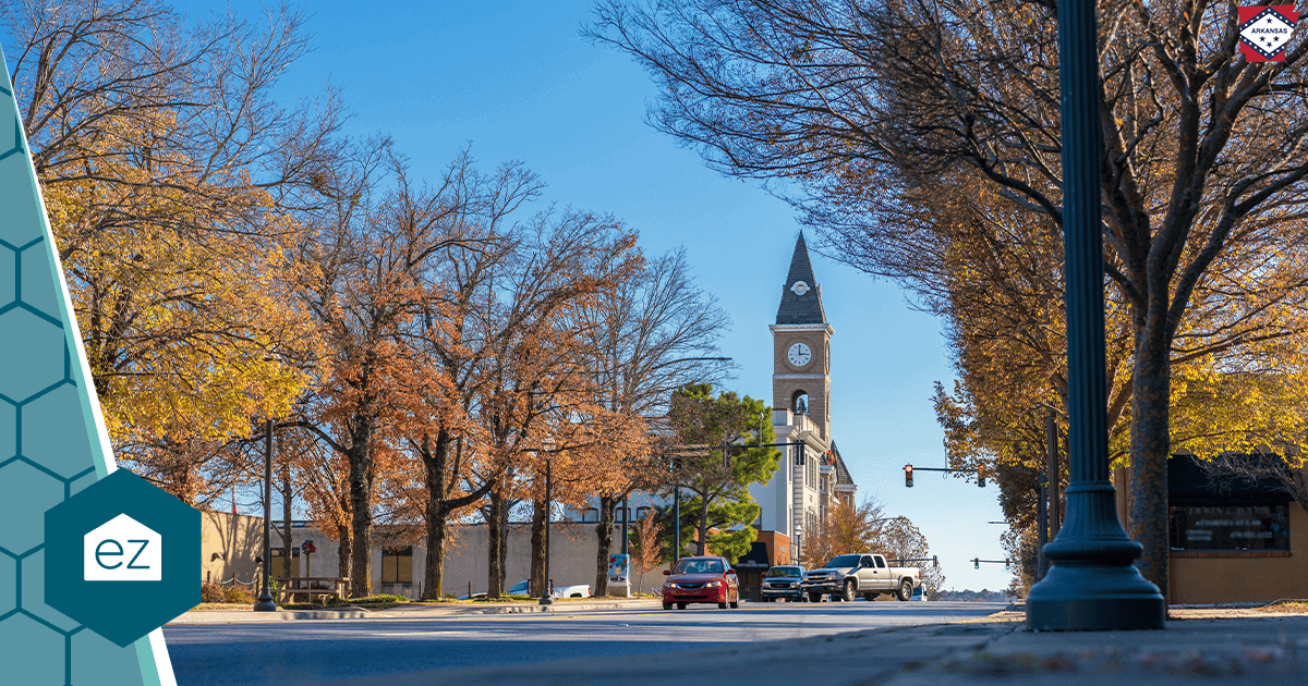 A street scene in downtown Bentonville, Arkansas with a clock tower and autumn trees.