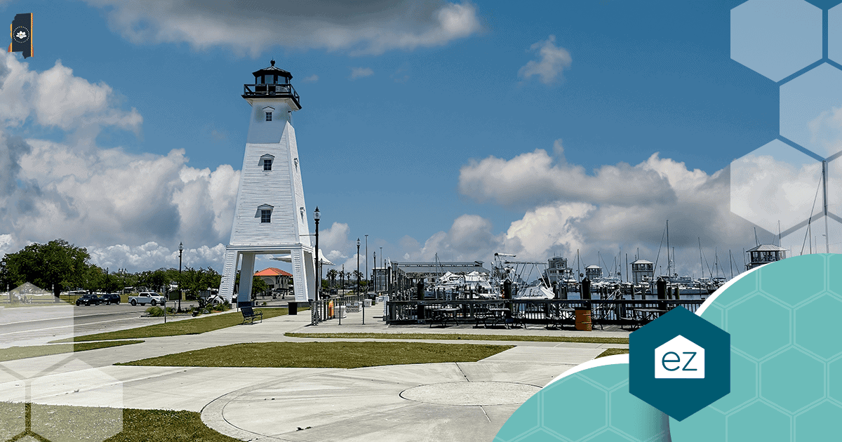 White Biloxi lighthouse beside a Mississippi Gulf Coast marina under a blue sky