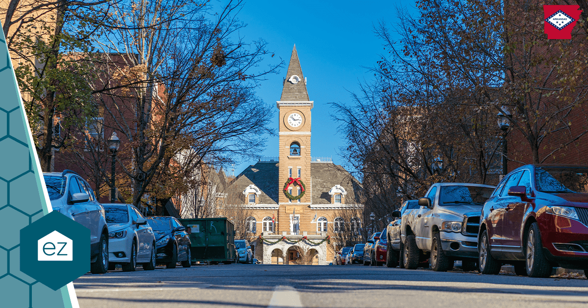 A brick clock-tower building on a tree-lined street in Fayetteville, Arkansas.