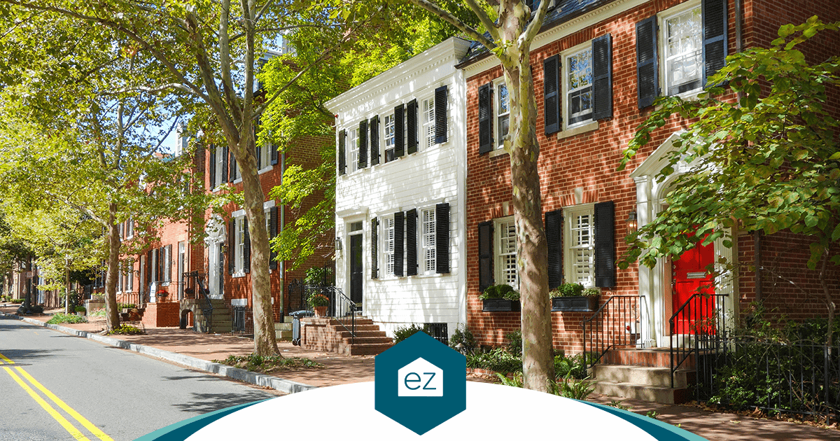 A tree-lined Washington DC street of brick rowhouses with black shutters and a red front door, a classic District residential block