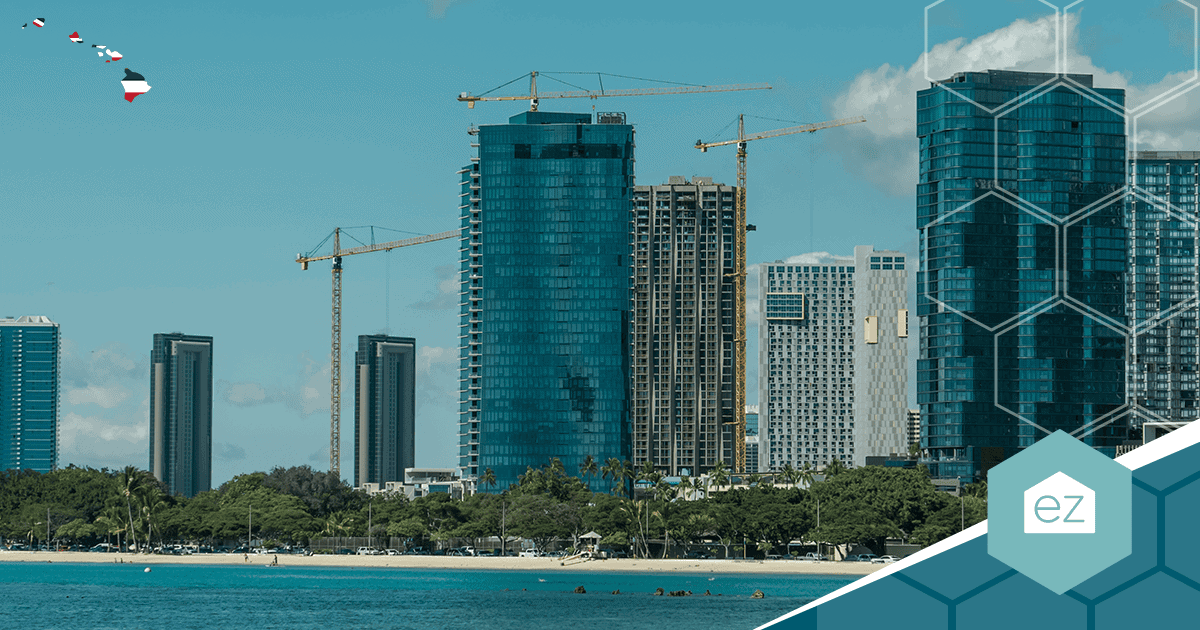 High-rise buildings and construction cranes along the Honolulu beachfront with swimmers in the ocean