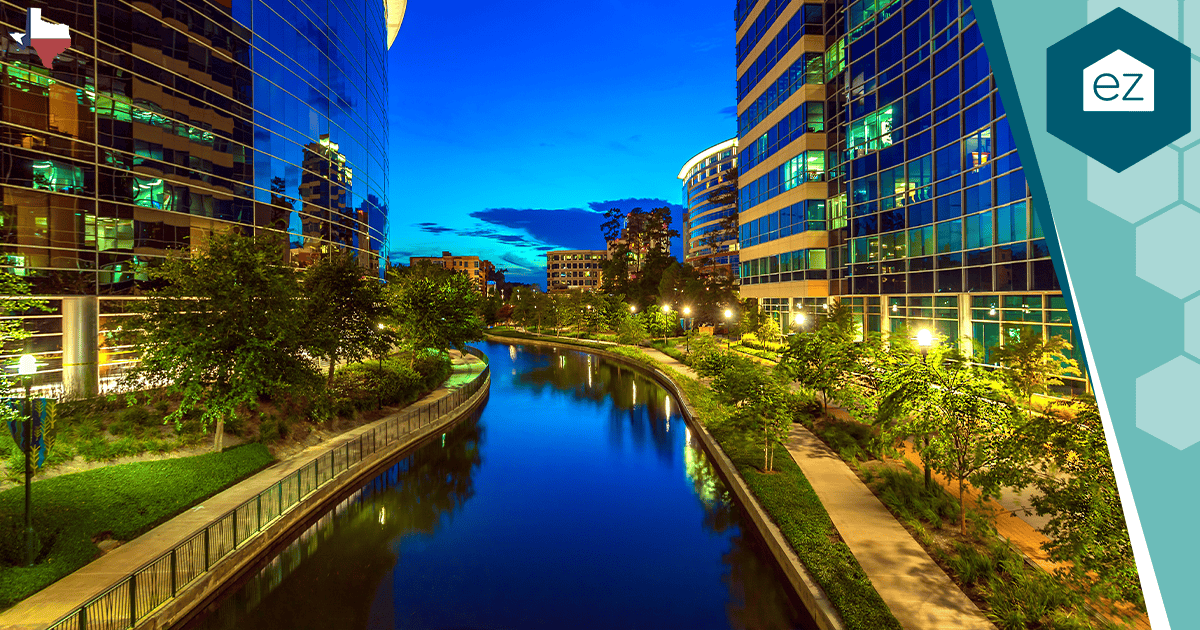 A modern San Antonio, Texas canal at dusk lined with glass office buildings.