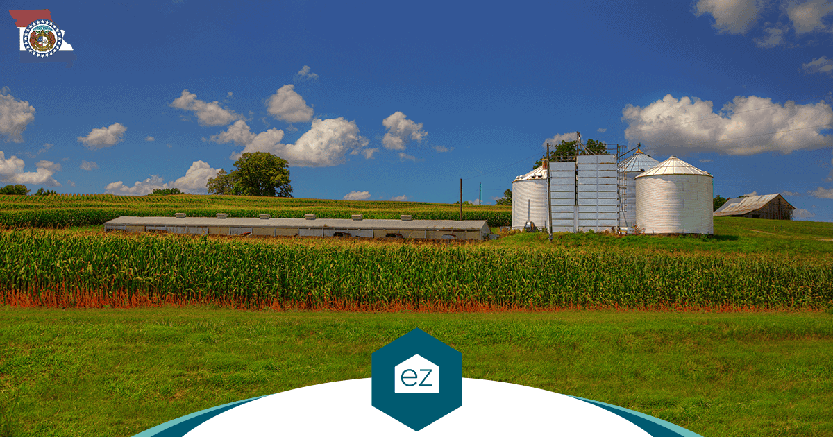 Missouri farm with cornfields and grain silos under a blue sky