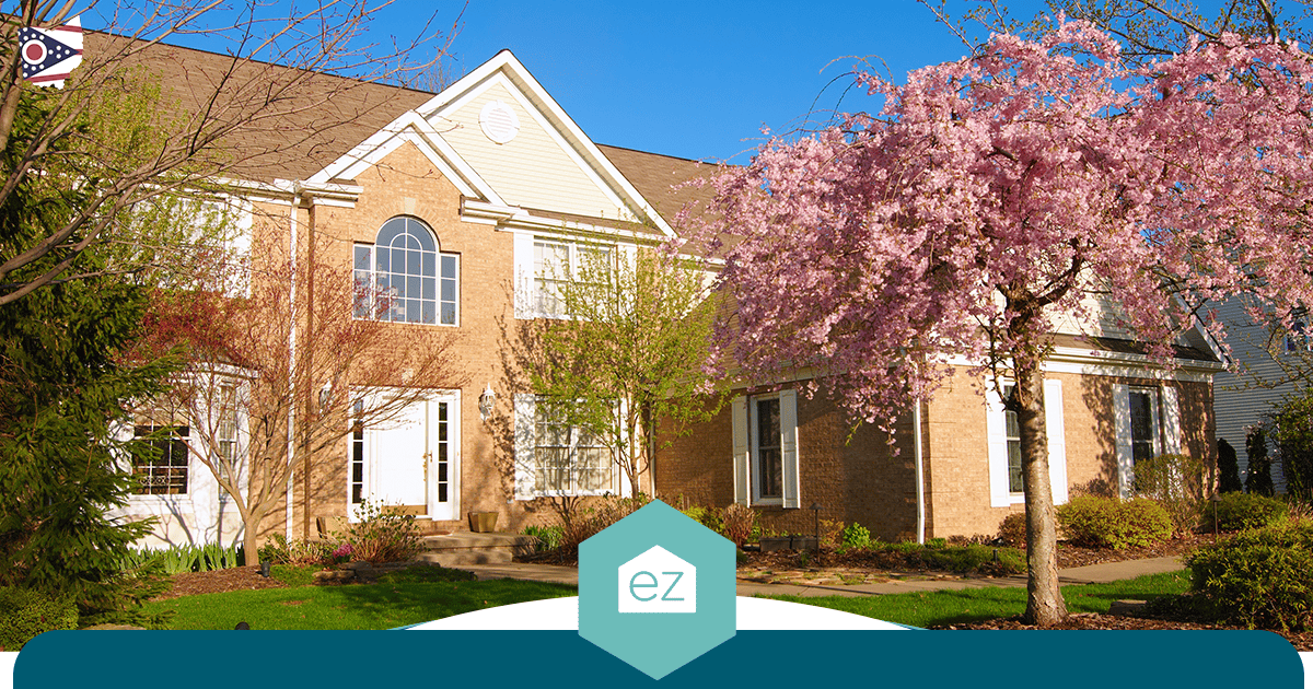 Two-story brick suburban home in Ohio surrounded by blooming trees under a clear sky