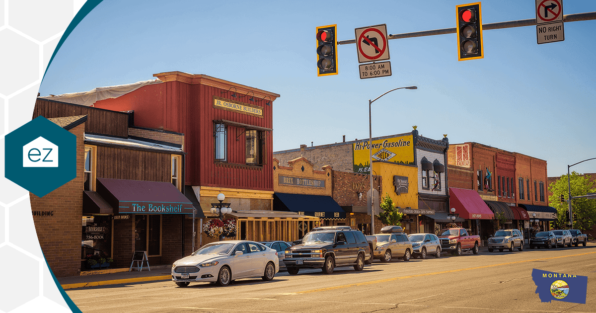 Downtown main street in a Montana town with brick storefronts and parked cars under a sunny sky