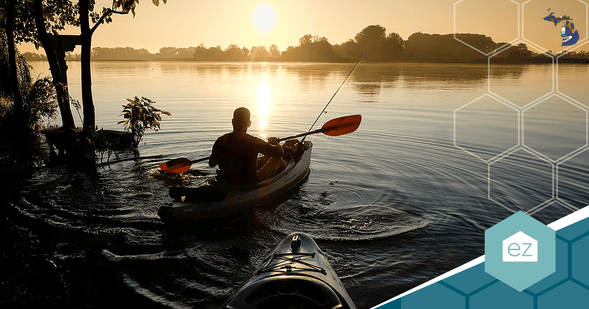Kayaker paddling on a calm Michigan lake at sunrise