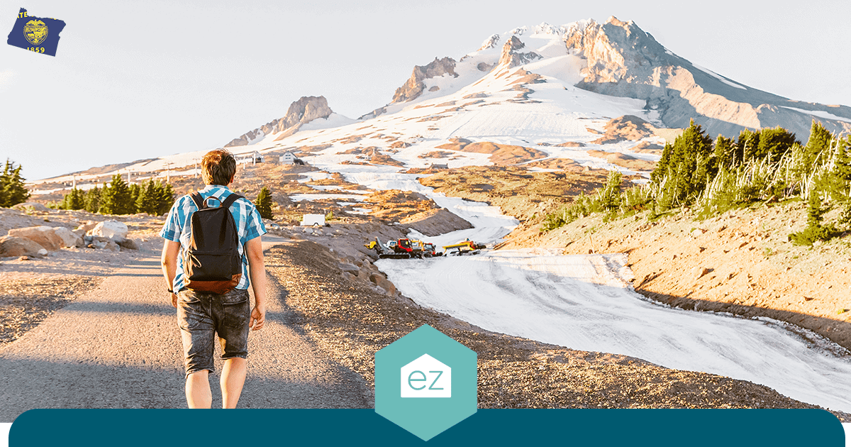 A hiker on a paved trail heading toward snow-covered Mount Hood in Oregon