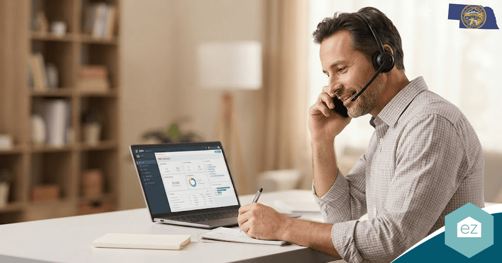 Man wearing a headset sits at a desk, talking on the phone, writing notes, and viewing a financial dashboard on a laptop. A Nebraska state flag is visible in the top right corner, suggesting he may be working with Nebraska real estate leads.