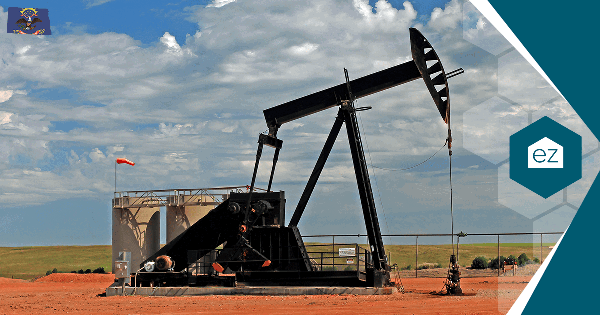 An oil pumpjack and storage tanks on a North Dakota field, part of the state's steady Bakken production