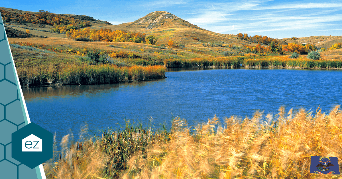 A prairie lake in North Dakota framed by tall grass and autumn hills