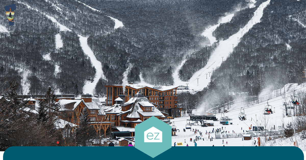 Vermont ski resort at the base of snow-covered mountains with ski runs, lifts, and wooden lodge buildings