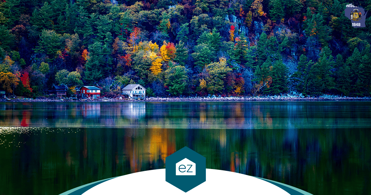 A calm Wisconsin lake reflecting autumn trees and shoreline houses