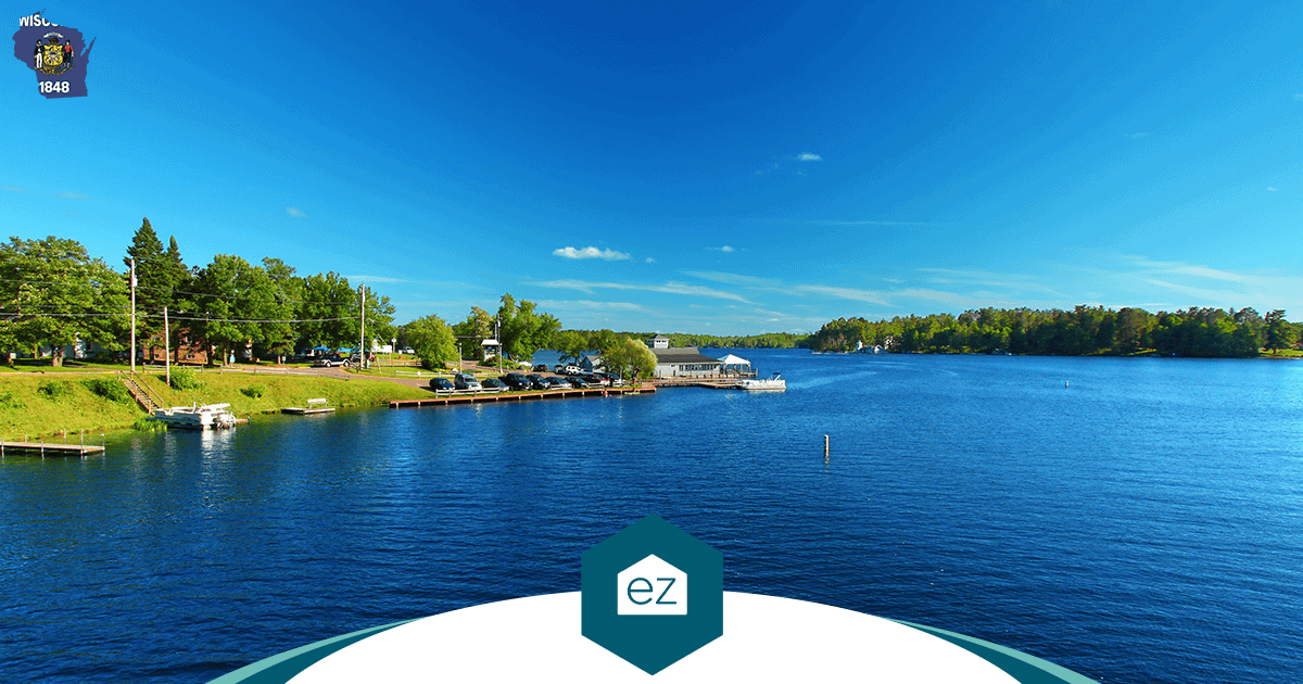 A clear blue Wisconsin lake with small boats docked along a tree-lined shoreline