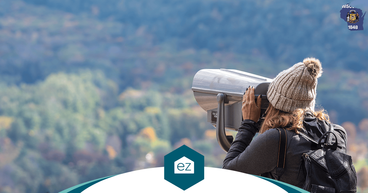 A visitor looking through a coin-operated viewer over a forested Wisconsin landscape