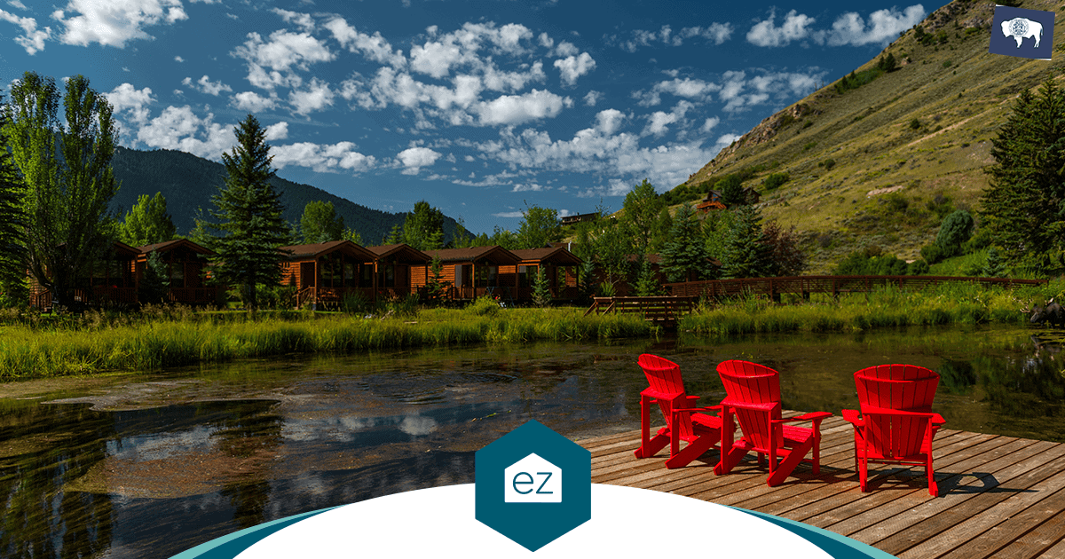Adirondack chairs on a dock facing cabins and a mountain in scenic Wyoming